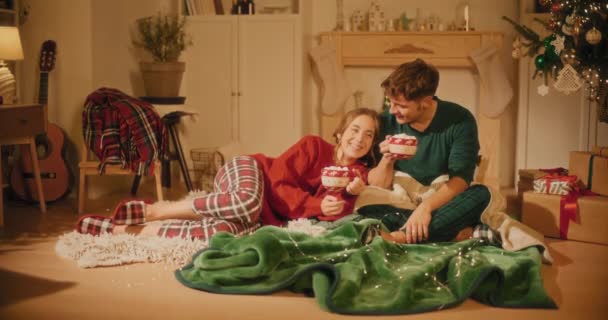 Heteroseksueel koppel met kopjes marshmallows in de woonkamer tijdens kerstavond - Video