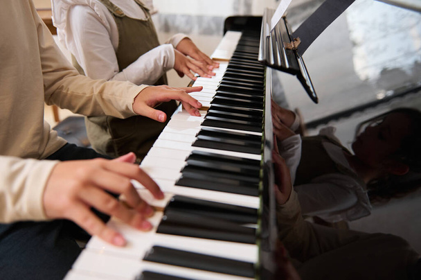 Close-up das mãos de duas crianças, menino e menina tocando música no piano de cauda. Crianças dedos em ébano e marfim chaves. Lição musical - Foto, Imagem