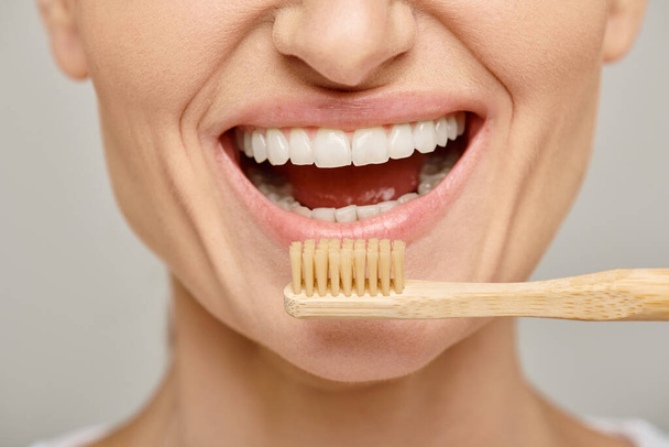 Schnappschuss einer glücklichen Frau in den 30er Jahren mit weißen gesunden Zähnen, die eine Bambuszahnbürste hält, offenen Mund - Foto, Bild