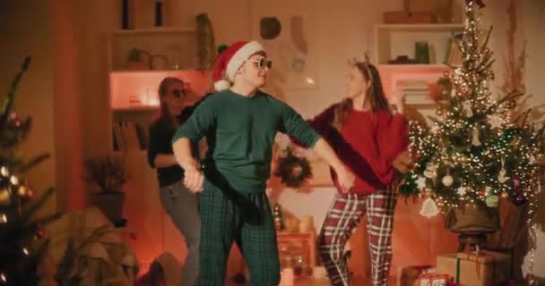 Young man enjoys dancing with female friends at home during Christmas holiday - Footage, Video
