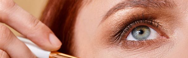 close up banner, redhead woman applying sparkling glitter on cheek with makeup brush on beige - Foto, Bild
