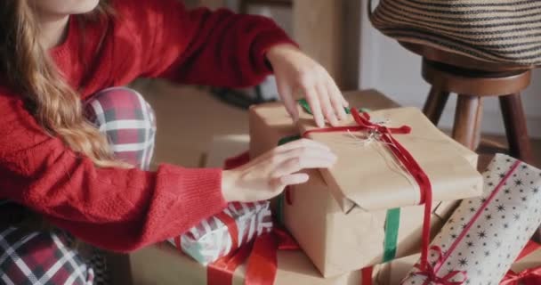 Środkowa część kobiety organizującej zapakowane prezenty świąteczne w jasnym domu - Materiał filmowy, wideo