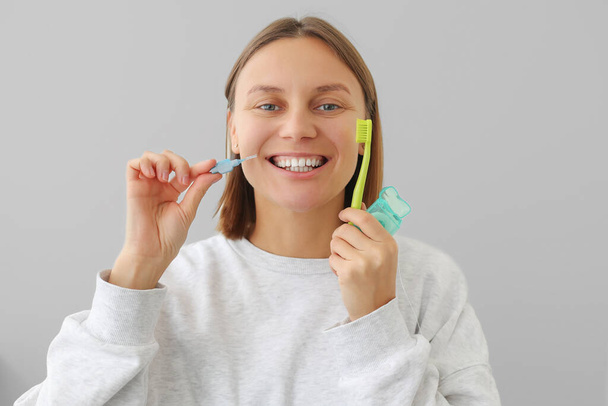 Frau mit weißen Zähnen hält Zahnseide, Zahnbürste und Interdentalbürste, um Mundkrankheiten vorzubeugen. Gesundheitszahnheilkunde und Mundhygienekonzept. Karies-Prävention im Alltag. - Foto, Bild