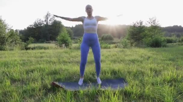 Oefeningen buiten, Silhouet van een meisje in legging en een top bij zonsondergang doen oefeningen. Hoge kwaliteit 4k beeldmateriaal - Video