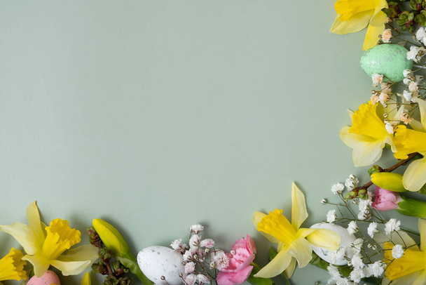 Voorjaarsbloemen en paaseieren grenzen aan groene achtergrond met kopieerruimte. Pasen wenskaart sjabloon. - Foto, afbeelding