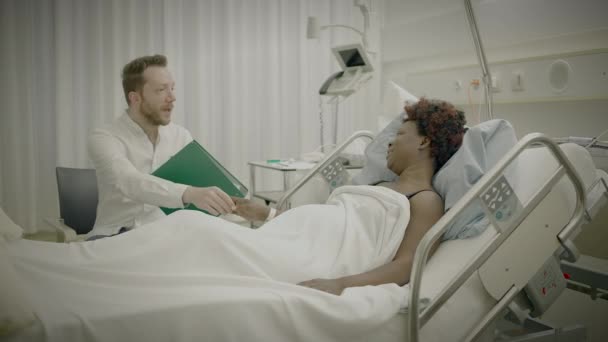 Médico visita a paciente en habitación del hospital explicando tratamiento médico de la curación de la salud - Imágenes, Vídeo