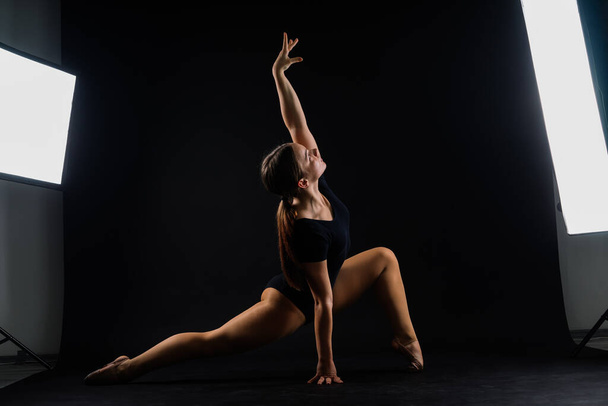 Красивая танцовщица спортивной аэробики позирует на белом и черном фоне студии - Фото, изображение
