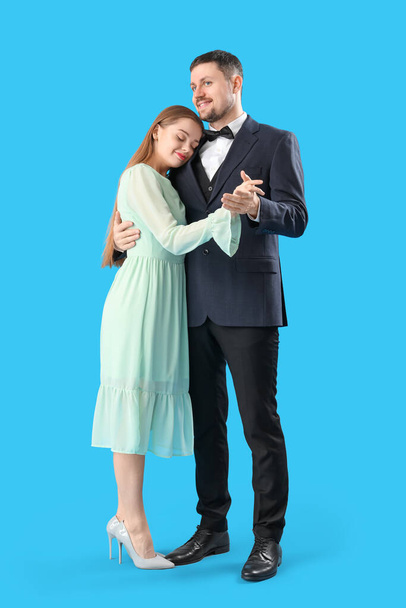 Elegante pareja joven bailando sobre fondo azul - Foto, Imagen