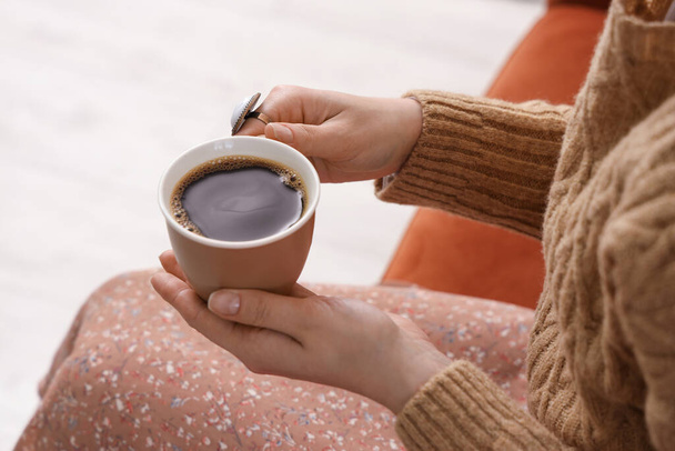 Frau sitzt auf gemütlichem Sofa und hält Tasse leckeren Kaffee - Foto, Bild