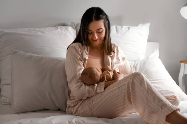 Genç bir kadın gece bebeğini yatak odasında emziriyor. - Fotoğraf, Görsel