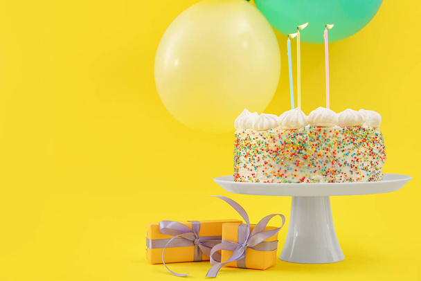 Stand with yummy cake and Birthday decoration on yellow background - Photo, Image