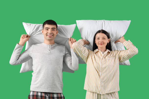 Jeune couple avec des oreillers sur fond vert - Photo, image