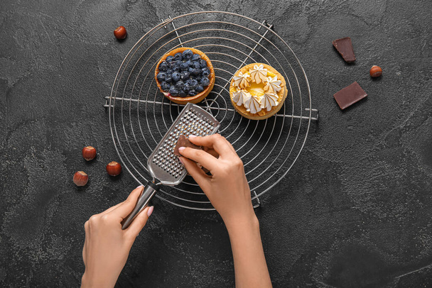 Ženské cukrovinky zdobí chutné dorty na černém pozadí - Fotografie, Obrázek