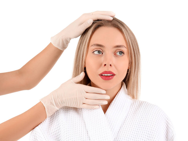 Beautician examining face of young woman on white background - Photo, Image