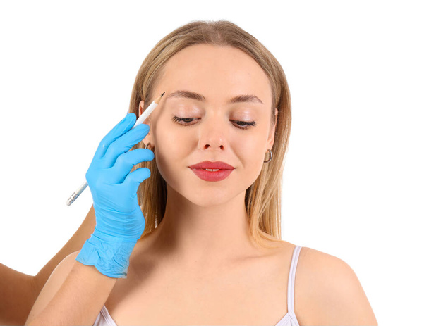 Beautician εφαρμογή σημάδια στο πρόσωπο της νεαρής γυναίκας σε λευκό φόντο - Φωτογραφία, εικόνα
