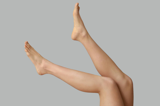 Πόδια της όμορφης νεαρής γυναίκας μετά την αποτρίχωση σε γκρι φόντο - Φωτογραφία, εικόνα