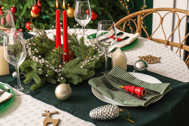 Elegante ajuste de mesa con corona de Navidad y velas encendidas, primer plano - Foto, imagen