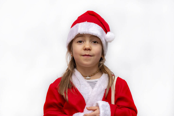 Ritratto di ragazza bionda di 5 anni su sfondo bianco in costume da Babbo Natale, isolato. - Foto, immagini