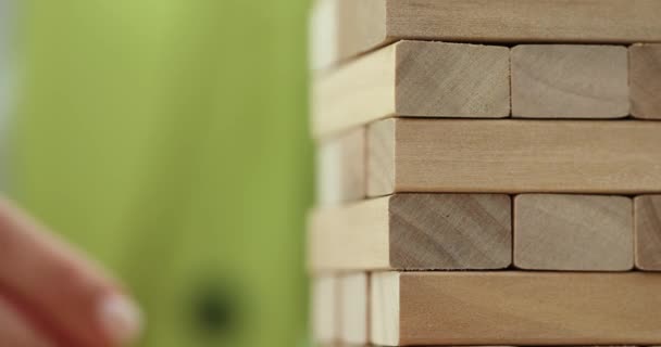 Torre de bloques de madera y mano persona toma un bloque. Riesgos económicos financieros - Metraje, vídeo