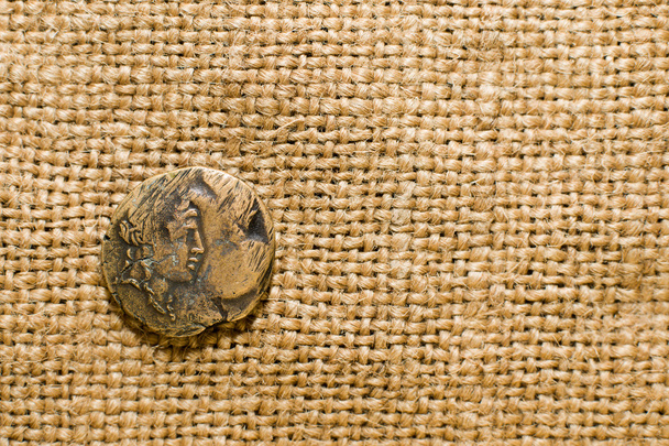 Античная монета с портретом императора на старой ткани
 - Фото, изображение