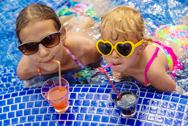 Дети пьют коктейль в бассейне. Выборочный фокус. Дети. - Фото, изображение