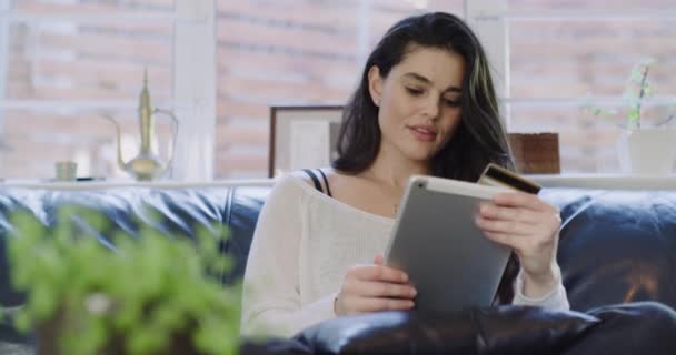 Woman, tablet and credit card for online payment at home, smiling and excited for purchase. Female person, couch and banking on technology or ecommerce, transaction and sale on website or promo. - Footage, Video