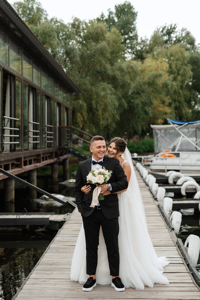 první setkání nevěsty a ženicha ve svatebních šatech na molu u vody - Fotografie, Obrázek