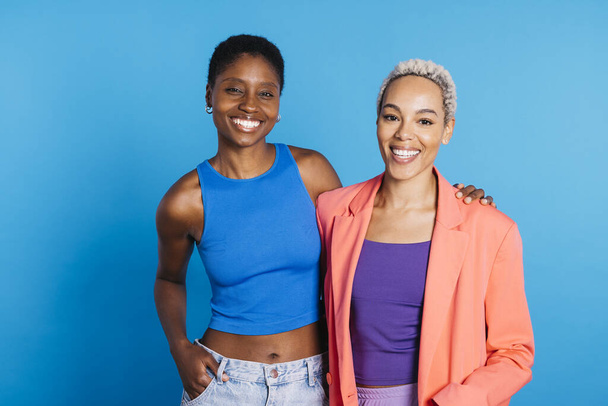 Portrait of a young female couple in front of a blue background at studio.Two women together at studio. - Photo, Image