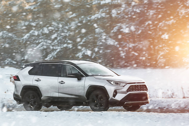 Χειμώνας αγκαλιάσει δεν κρατά κανένα εμπόδιο για αυτό το ισχυρό SUV όπως γλιστρά μέσα από το χιονισμένο έδαφος με χάρη και δύναμη που αναδεικνύει την κατάκτηση του ανθρώπου πάνω στη φύση. Λευκό φορτηγό αυτοκίνητο για το χειμώνα χιονισμένο δρόμο. - Φωτογραφία, εικόνα