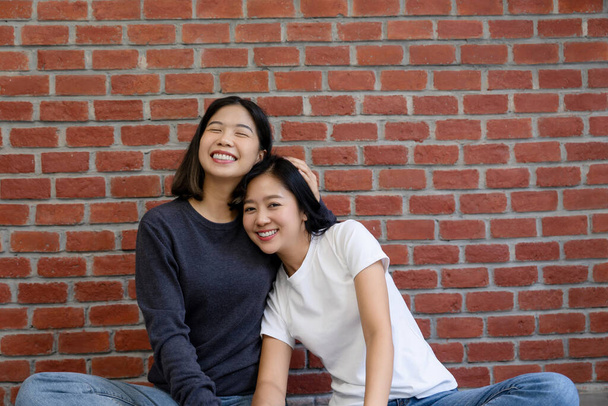 Retrato de um feliz e encantador casal LGBTQ asiático sentado em sua nova casa e sorrindo para a câmera. - Foto, Imagem
