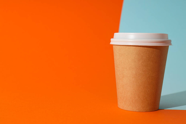 A paper cup with a lid on an orange background - Photo, Image