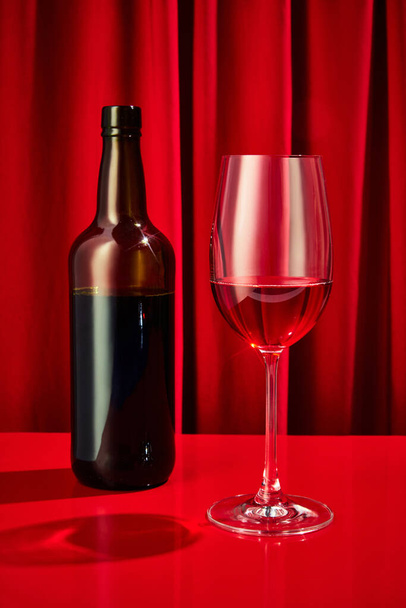 Close up photo of sweet red, pink seasoned wine served in high glass classy and bottle of wine on bar counter at restaurant. Concept of night life, party time, holidays, Valentines Day, celebration - Photo, Image