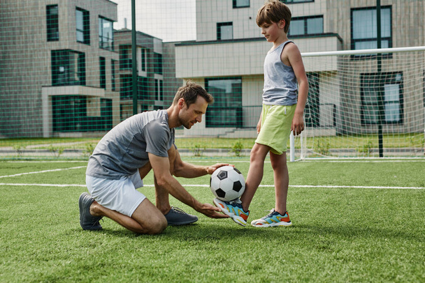 Портрет молодого отца, обучающего игре в футбол на открытом воздухе, копировальное пространство - Фото, изображение
