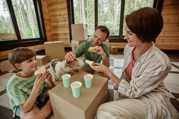 Щаслива сім'я переїжджає в новий будинок і насолоджується обідом з обіднім столом, копіювати простір - Фото, зображення