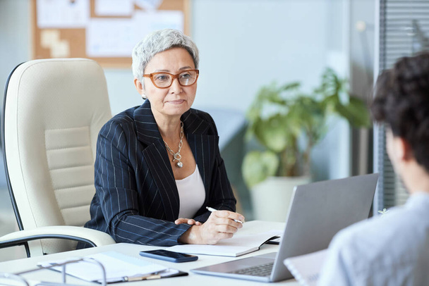 Πορτρέτο της ώριμης επιχειρηματία φορώντας γυαλιά μιλώντας με τον εργαζόμενο στη συνάντηση, αντίγραφο χώρο - Φωτογραφία, εικόνα