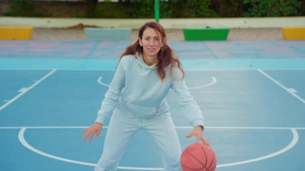Закройте кадры тренировок женщин-баскетболистов и упражнений на открытом воздухе на местной площадке. Молодая женщина тренируется прыгать с баскетбольным мячом. Медленный уличный баскетбол. - Кадры, видео