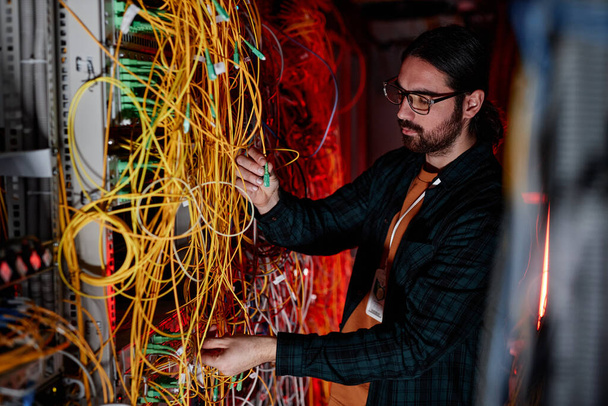 Seitenansicht Porträt eines bärtigen Mannes als Systemadministrator, der ein Servernetzwerk einrichtet und Wartungsarbeiten erledigt - Foto, Bild