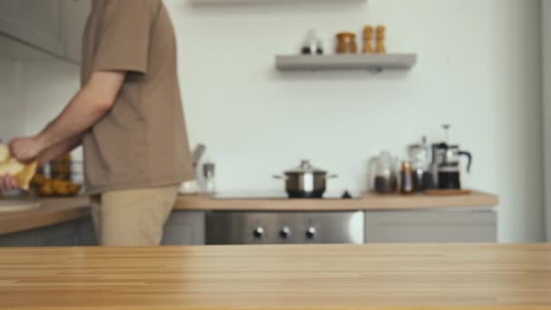Порожній ударний знімок невпізнаваного чоловіка, що змочує тканину і протирає і прибирає кухонний стіл в сучасній квартирі - Кадри, відео
