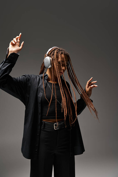 20代の若いアフリカ系アメリカ人女性がワイヤレスヘッドフォンで音楽を聴きながら踊り - 写真・画像