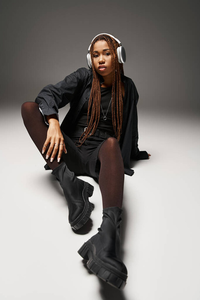 20 'li yaşlarda şık bir Afro-Amerikan kadın. Rasta saçlı. Stüdyoda kulaklıkla müzik dinliyor. - Fotoğraf, Görsel