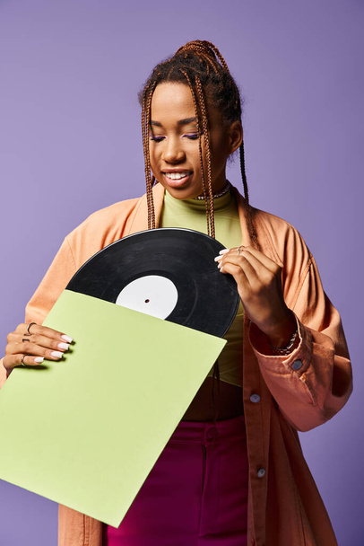 joven afroamericana de unos 20 años con rastas admirando el disco de vinilo con una expresión alegre - Foto, imagen