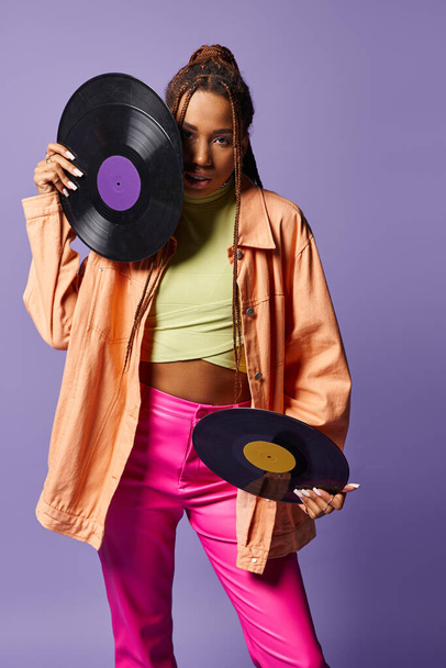 young african american girl in her 20s with dreadlocks holding vinyl discs on purple backdrop - Photo, Image