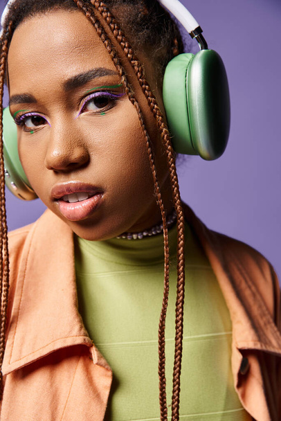 heitere afrikanisch-amerikanische Mädchen in den 20er Jahren Musik hören in drahtlosen Kopfhörern auf lila Hintergrund - Foto, Bild