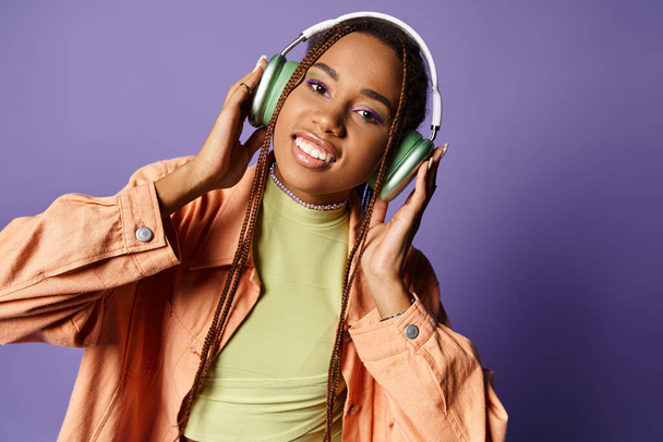 menina americana africana satisfeito em 20s ouvir música em fones de ouvido sem fio e olhando para a câmera - Foto, Imagem
