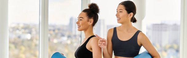 Onnellinen monikulttuurinen nuoret naiset heidän 20s seisoo jooga matot studio, post-workout banneri - Valokuva, kuva