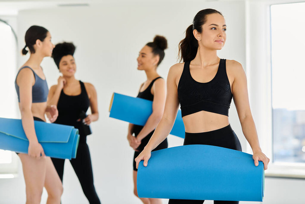 zaměření na brunetky mladá žena ve sportovním oblečení stojící s fitness podložkou ve studiu pilates - Fotografie, Obrázek