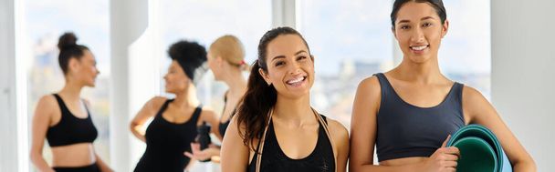 banner of happy diverse female friends in active wear smiling at camera after pilates workout - Photo, Image