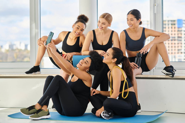 Beş kişilik bir grup ve spor giyim sektöründe çok kültürlü kadınlar yoga dersinden sonra selfie çekiyorlar. - Fotoğraf, Görsel