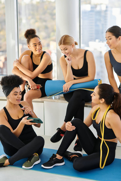 Mutlu Afrikalı Amerikalı kadın pilates stüdyosundaki antrenmandan sonra arkadaşlarına akıllı telefon gösteriyor. - Fotoğraf, Görsel