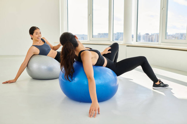 gelukkige divers vrouwen trainen op fitness ballen tijdens pilates klasse, vrouwelijke vrienden en sport - Foto, afbeelding